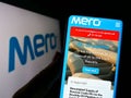 Person holding cellphone with website of Czech oil pipeline company MERO CR a.s. on screen in front of logo.