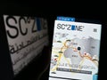Person holding cellphone with website of Egyptian Suez Canal Economic Zone (SCZONE) on screen in front of logo.