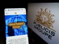 Person holding cellphone with website of French advertising company Publicis Groupe S.A. on screen with logo.