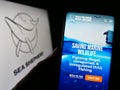 Person holding cellphone with website of Sea Shepherd Conservation Society (SSCS) on screen in front of logo.