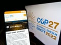 Person holding cellphone with website of 2022 UN Climate Change Conference (COP27) on screen in front of logo.