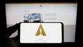 Person holding mobile phone with logo of Academy of Motion Picture Arts and Sciences (AMPAS) on screen with webpage.