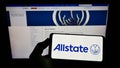 Person holding mobile phone with logo of American insurance company The Allstate Corporation on screen in front of webpage. Royalty Free Stock Photo