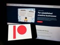 Person holding mobile phone with logo of American membership platform company Patreon Inc. on screen in front of web page.