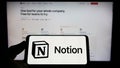 Person holding mobile phone with logo of American software company Notion Labs Inc. on screen in front of web page. Royalty Free Stock Photo