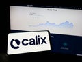 Person holding mobile phone with logo of Australian technology company Calix Limited on screen in front of web page.