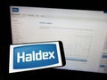 Person holding mobile phone with logo of automotive company Haldex Europe SAS on screen in front of business web page. Royalty Free Stock Photo