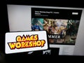 Person holding mobile phone with logo of British company Games Workshop Group plc on screen in front of business web page.
