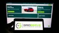 Person holding mobile phone with logo of British company GRIDSERVE Sustainable Energy Ltd on screen in front of web page.