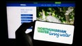 Person holding mobile phone with logo of British company Northumbrian Water Limited on screen in front of web page. Royalty Free Stock Photo