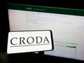 Person holding mobile phone with logo of chamicals company Croda International plc on screen in front of business web page. Royalty Free Stock Photo