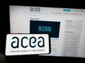 Person holding mobile phone with logo of European Automobile Manufacturers Association (ACEA) on screen with web page.