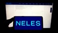 Person holding mobile phone with logo of Finnish flow control company Neles Oyj on screen in front of business web page.