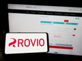 Person holding mobile phone with logo of Finnish games company Rovio Entertainment Oyj on screen in front of web page.