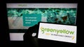 Person holding mobile phone with logo of French energy company GreenYellow SAS on screen in front of business web page. Royalty Free Stock Photo