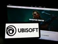 Person holding mobile phone with logo of French video game company Ubisoft Entertainment SA on screen in front of webpage. Royalty Free Stock Photo