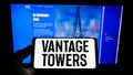 Person holding mobile phone with logo of German infrastructure company Vantage Towers AG on screen in front of web page.