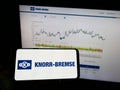 Person holding mobile phone with logo of German manufacturing company Knorr-Bremse AG on screen in front of web page. Royalty Free Stock Photo
