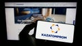 Person holding mobile phone with logo of Kazakh uranium mining company Kazatomprom on screen in front of business webpage. Royalty Free Stock Photo