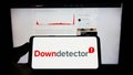 Person holding mobile phone with logo of online platform Downdetector (Ookla LLC) on screen in front of web page. Royalty Free Stock Photo