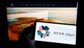 Person holding mobile phone with logo of Saudi Arabian property developer NEOM Company on screen in front of web page. Royalty Free Stock Photo