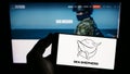 Person holding mobile phone with logo of Sea Shepherd Conservation Society (SSCS) on screen in front of web page.