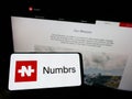 Person holding mobile phone with logo of Swiss fintech company Numbrs Personal Finance AG on screen in front of web page. Royalty Free Stock Photo