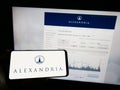 Person holding mobile phone with logo of US company Alexandria Real Estate Equities Inc. on screen in front of web page.