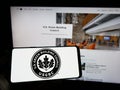 Person holding mobile phone with logo of US Green Building Council (USGBC) on screen in front of web page.