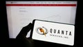 Person holding mobile phone with logo of US infrastructure company Quanta Services Inc. on screen in front of web page. Royalty Free Stock Photo