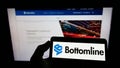 Person holding mobile phone with logo of US payment company Bottomline Technologies Inc. on screen in front of web page. Royalty Free Stock Photo
