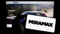 Person holding mobile phone with logo of US television production company Miramax LLC on screen in front of web page. Royalty Free Stock Photo