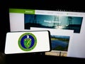 Person holding mobile phone with seal of United States Department of Energy (DOE) on screen in front of web page.