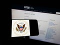 Person holding mobile phone with seal of US National Transportation Safety Board (NTSB) on screen in front of web page.