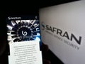 Person holding mobile phone with webpage of French aerospace company Safran S.A. on screen in front of logo. Royalty Free Stock Photo