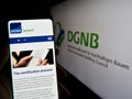 Person holding mobile phone with website of Deutsche Gesellschaft fÃ¼r Nachhaltiges Bauen (DGNB) on screen.