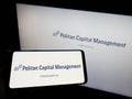 Person holding smartphone with logo of American company Politan Capital Management LP on screen in front of website.
