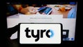 Person holding smartphone with logo of Australian fintech company Tyro Payments Limited on screen in front of website.