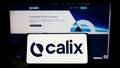 Person holding smartphone with logo of Australian technology company Calix Limited on screen in front of website. Royalty Free Stock Photo