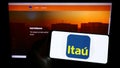 Person holding smartphone with logo of Brazilian company Itau Unibanco Holding S.A. on screen in front of website. Royalty Free Stock Photo