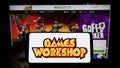 Person holding smartphone with logo of British company Games Workshop Group plc on screen in front of website.