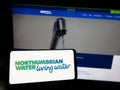 Person holding smartphone with logo of British company Northumbrian Water Limited on screen in front of website. Royalty Free Stock Photo