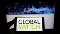 Person holding smartphone with logo of British data center company Global Switch Limited on screen in front of website.