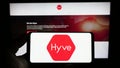 Person holding smartphone with logo of British event management company Hyve Group plc on screen in front of website.