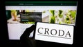 Person holding smartphone with logo of chamicals company Croda International plc on screen in front of website. Royalty Free Stock Photo