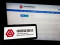 Person holding smartphone with logo of China Securities Regulatory Commission (CSRC) on screen in front of website.