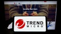 Person holding smartphone with logo of cybersecurity company Trend Micro Inc. on screen in front of website. Royalty Free Stock Photo