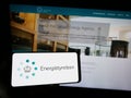 Person holding smartphone with logo of Danish energy agency Energistyrelsen on screen in front of website.