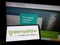 Person holding smartphone with logo of French energy company GreenYellow SAS on screen in front of website.