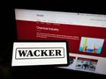 Person holding smartphone with logo of German chemical company Wacker Chemie AG on screen in front of website.